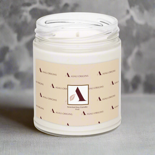Candle in a glass jar with a n Asali Origins abel on a gray background