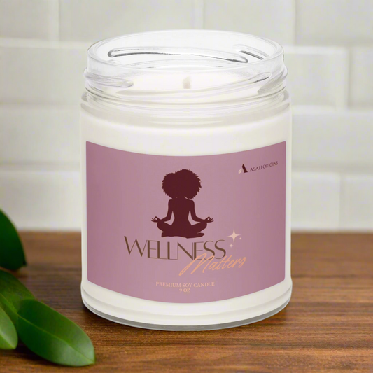 Candle in a glass jar with a 'Wellness Matters' label on a wooden surface.