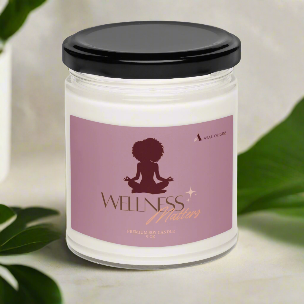 Candle jar with a 'Wellness Matters' label on a light background with green leaves.