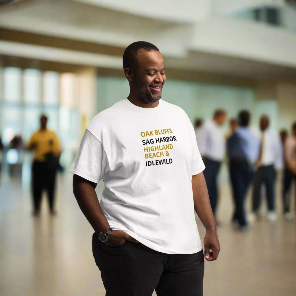 Man wearing a white t-shirt with text, standing in a blurred indoor setting with people.