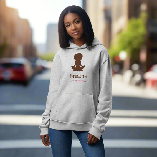 Woman wearing a gray hoodie with a 'Breathe' design on a city street.